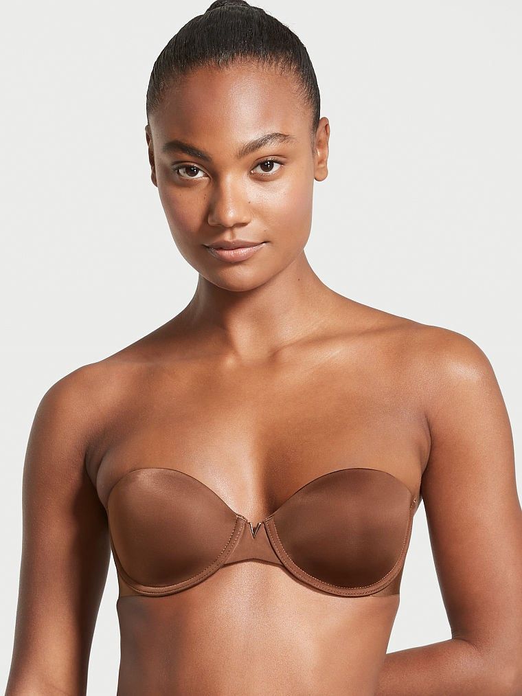 Modelka prezentuje biustonosz lekko usztywniany bez ramiączek Sexy Illusions Strapless. Produkt ma kolor brązowy i pochodzi z kolekcji Victoria's Secret Bare.