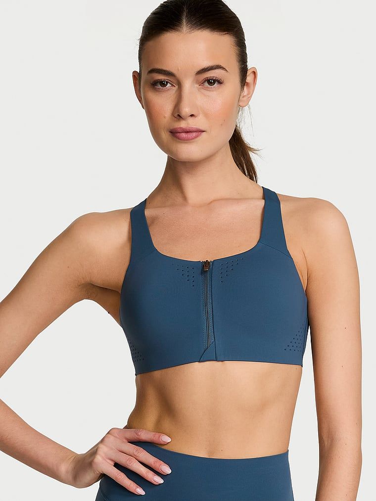 Modelka prezentuje biustonosz sportowy z maksymalnym podtrzymaniem z suwakiem Featherweight Max Front-Close. Produkt ma kolor niebieski i pochodzi z kolekcji VSX.