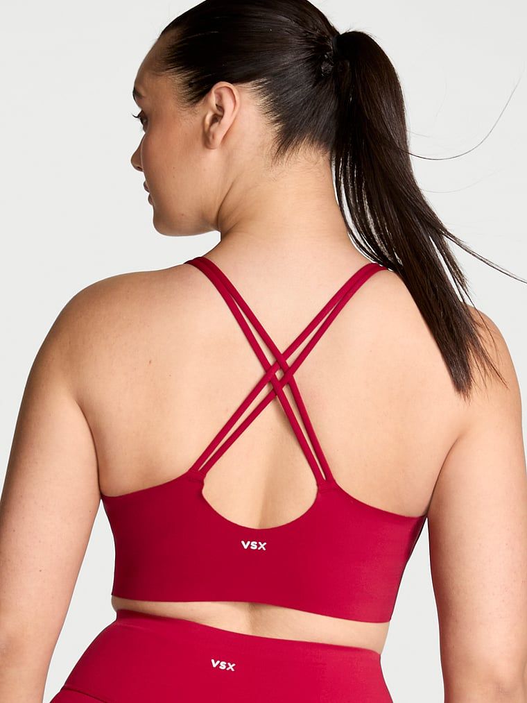 Modelka prezentuje biustonosz sportowy z lekkim wsparciem Elevate Strappy. Produkt ma kolor czerwony i pochodzi z kolekcji VSX.