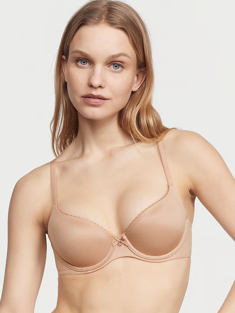 Modelka prezentuje biustonosz lekko usztywniany Smooth Demi. Produkt ma kolor beżowy i pochodzi z kolekcji Body by Victoria.