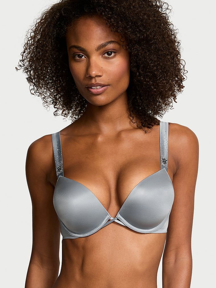 Modelka prezentuje biustonosz push-up powiększający o 2 rozmiary Bombshell Scattered Shine Strap. Produkt ma kolor szary i pochodzi z kolekcji Very Sexy.
