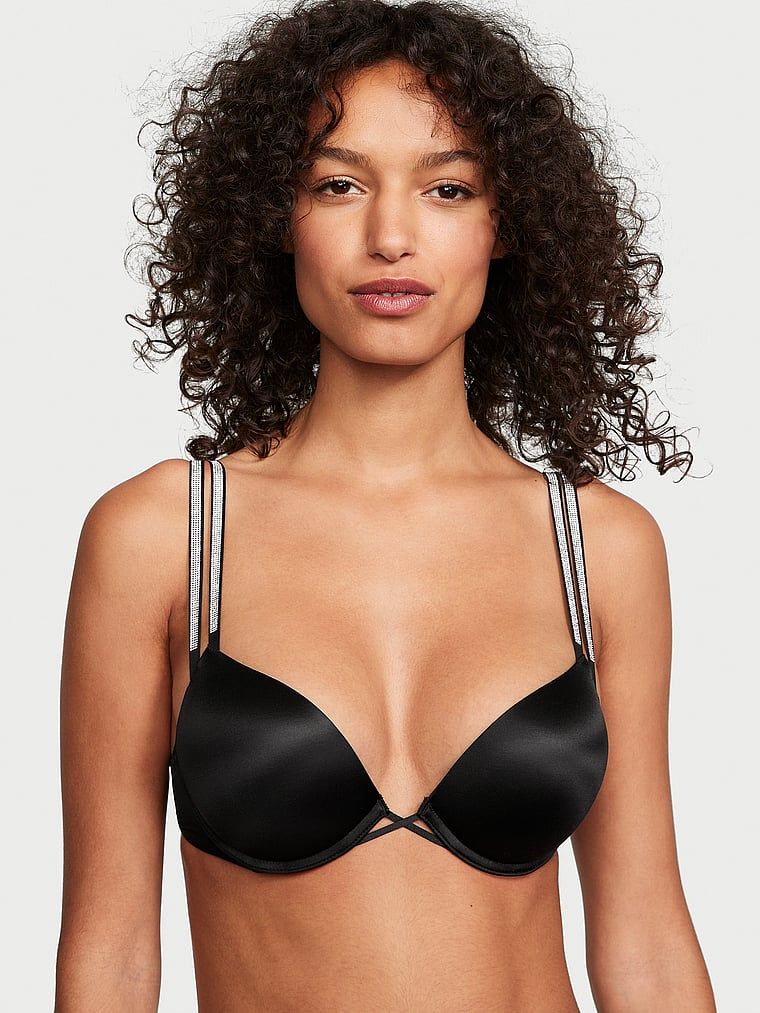 Modelka prezentuje biustonosz push-up powiększający o 2 rozmiary Bombshell Double Shine Strap. Produkt ma kolor czarny i pochodzi z kolekcji Very Sexy.