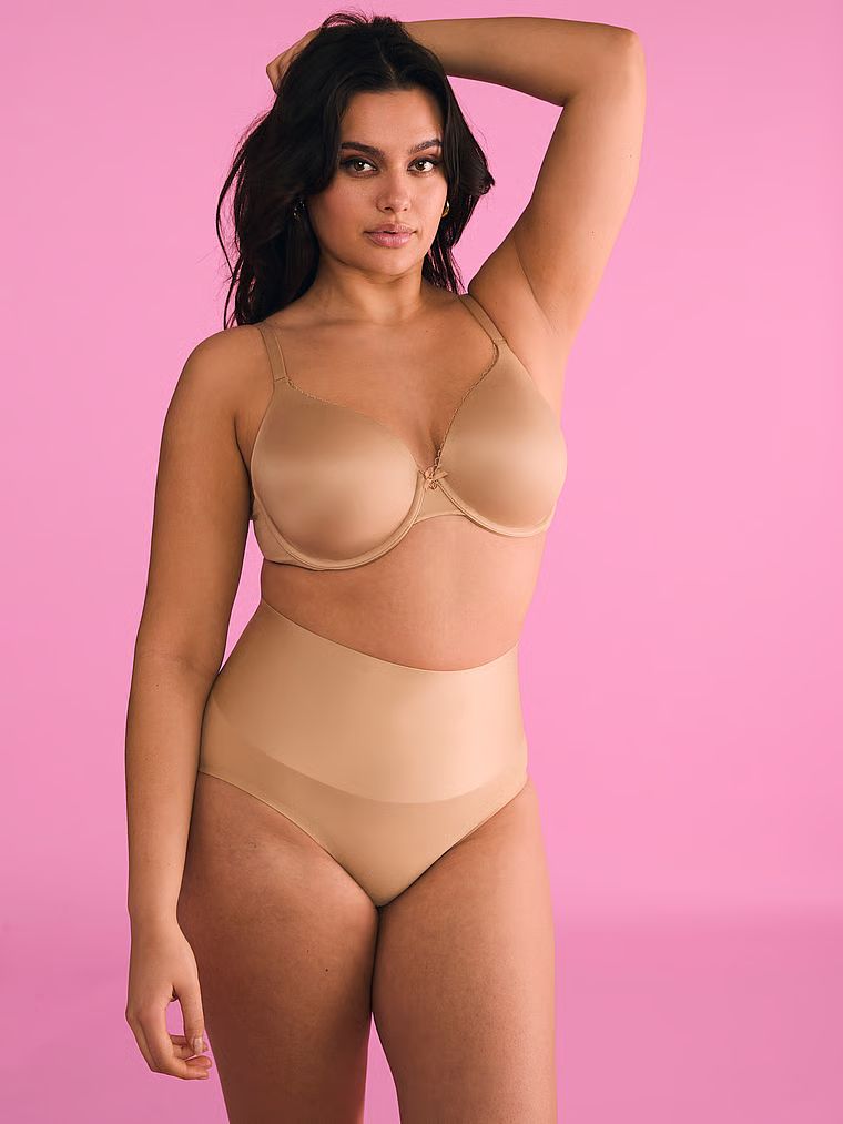 Modelka prezentuje biustonosz lekko usztywniany z mocno zabudowanymi miseczkami Infinity Edge. Produkt ma kolor beżowy i pochodzi z kolekcji Body by Victoria.