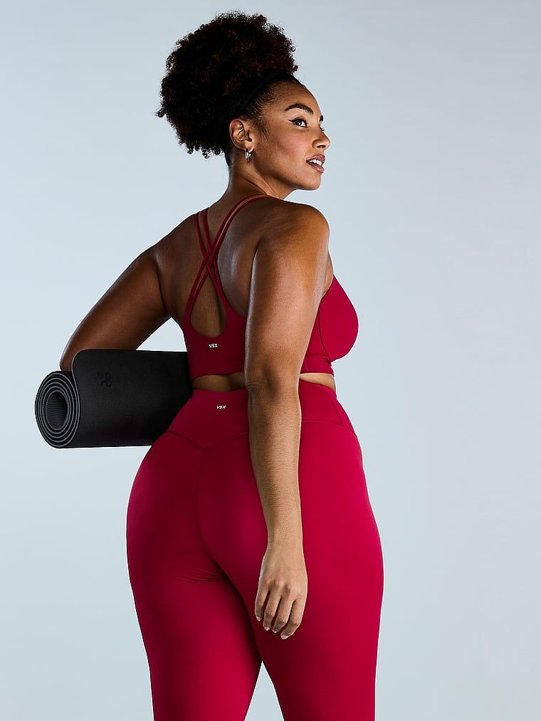 Modelka prezentuje biustonosz sportowy z lekkim wsparciem Elevate Strappy. Produkt ma kolor czerwony i pochodzi z kolekcji VSX.