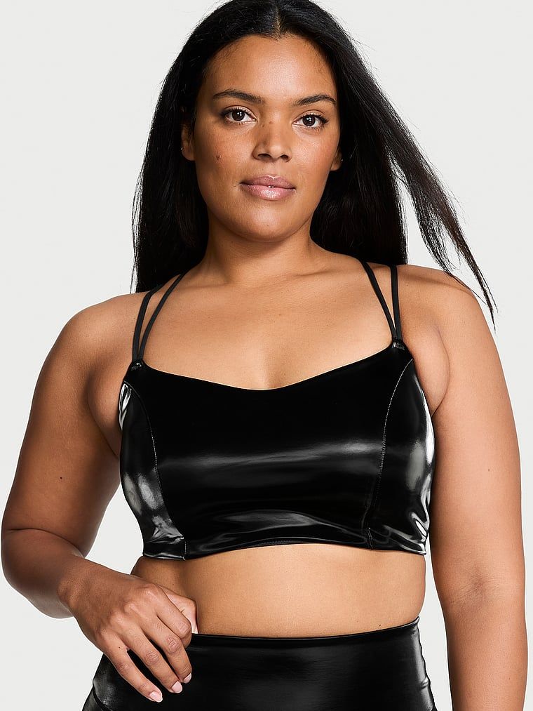 Modelka prezentuje biustonosz sportowy z lekkim wsparciem VSX Liquid Shine. Produkt ma kolor czarny i pochodzi z kolekcji VSX.