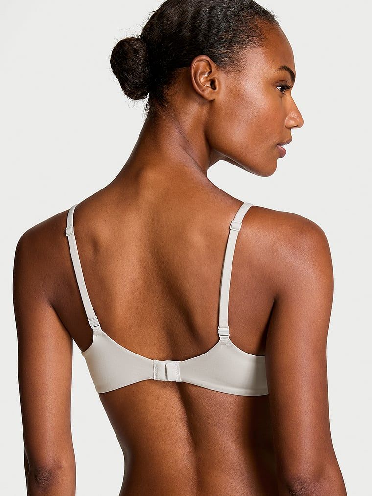 Modelka prezentuje biustonosz nieusztywniany Invisible Lift Smooth Demi. Produkt ma kolor szary i pochodzi z kolekcji Body by Victoria.