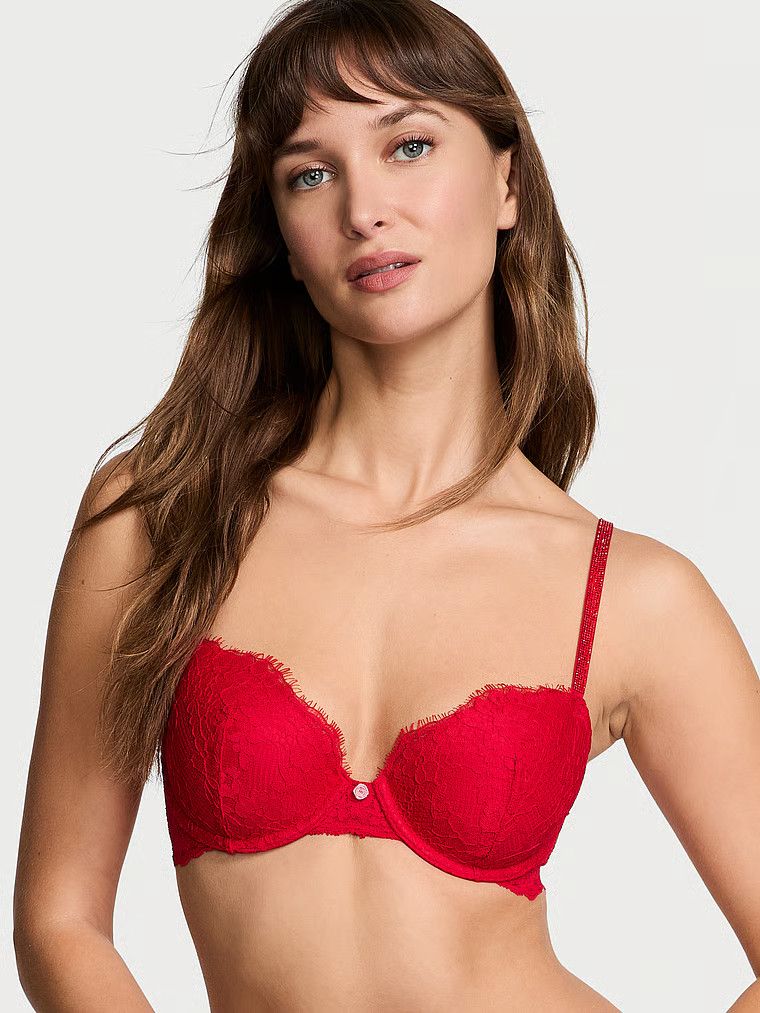 Modelka prezentuje biustonosz lekko usztywniany koronkowy z błyszczącymi ramiączkami Twinkle Strap Demi. Produkt ma kolor czerwony i pochodzi z kolekcji Dream Angels.