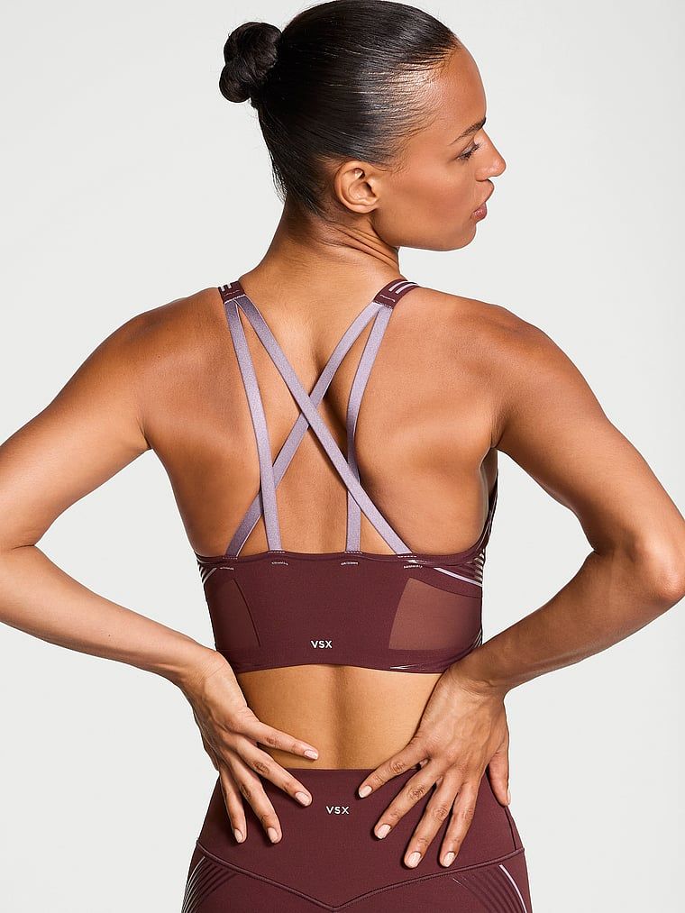 Modelka prezentuje biustonosz sportowy z lekkim wsparciem i dekoltem VSX Elevate Refined Contours. Produkt ma kolor czerwony i pochodzi z kolekcji VSX.
