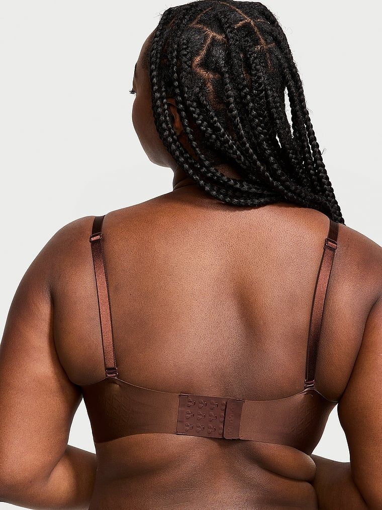 Modelka prezentuje biustonosz lekko usztywniany z głębokim dekoltem Open Plunge. Produkt ma kolor brązowy i pochodzi z kolekcji Victoria's Secret Bare.