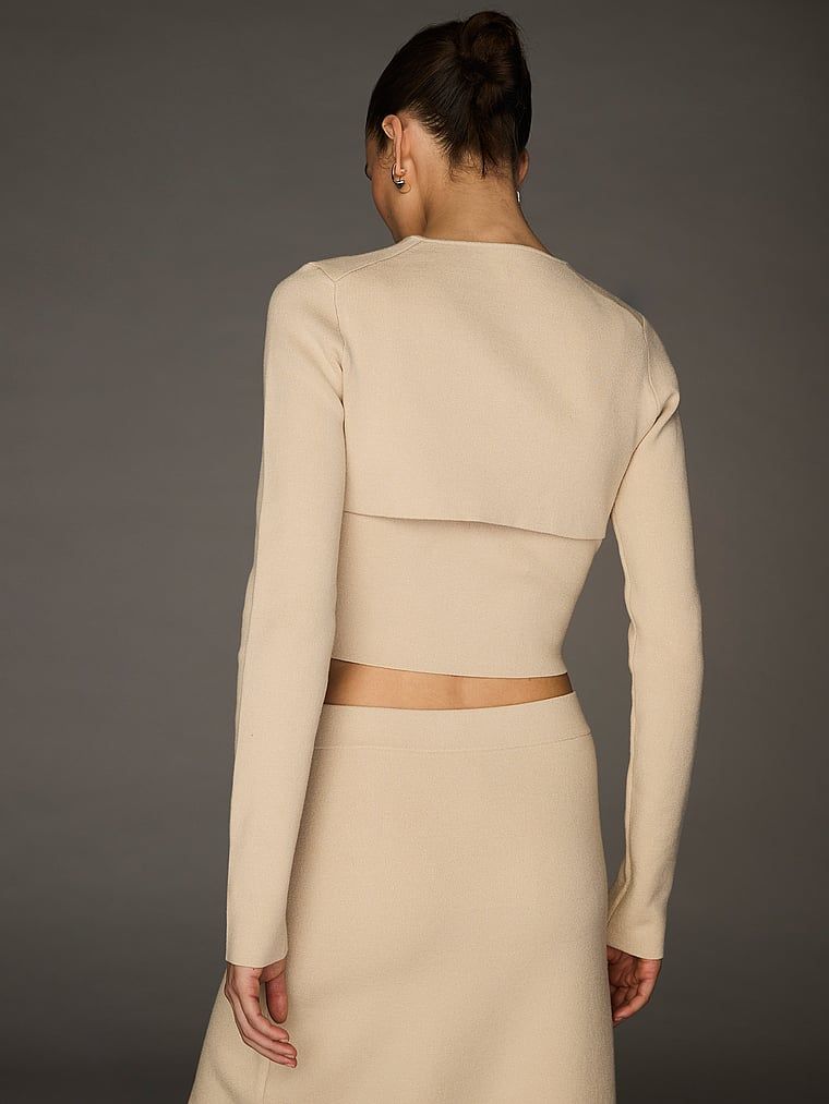 Sweterek kardigan krótki zapinany na haftki Atelier X Altuzarra. Produkt ma kolor beżowy i pochodzi z kolekcji Atelier Victoria's Secret x Altuzarra. 