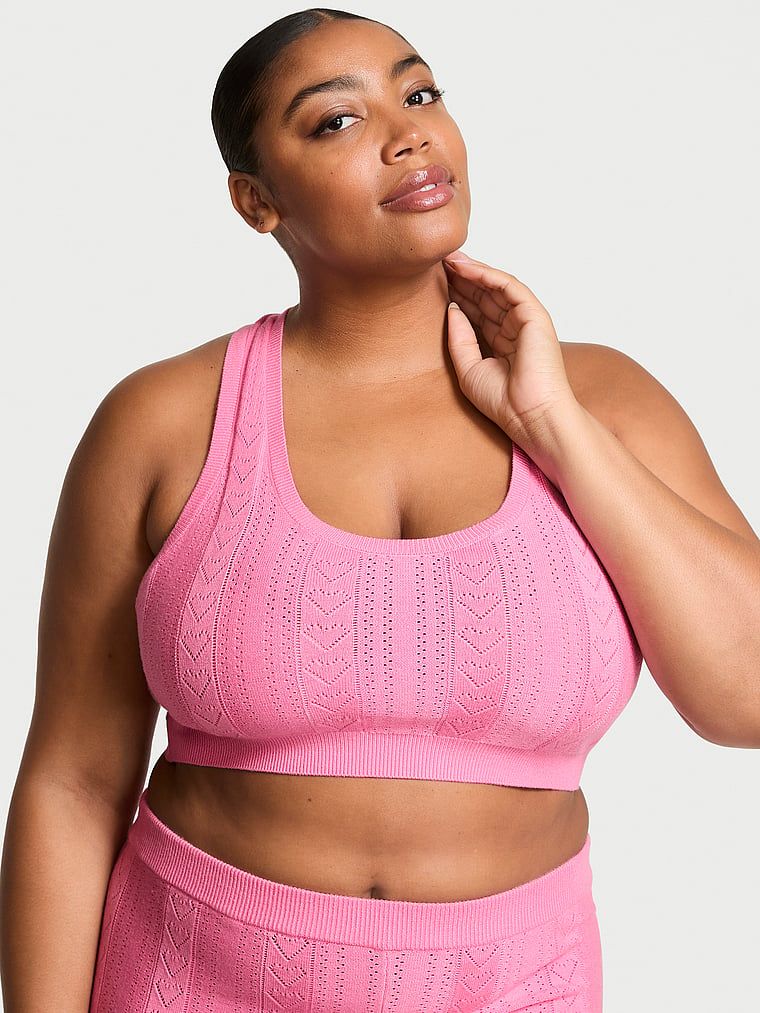 Modelka prezentuje biustonosz braletka z dziurkowanego materiału Luxe Heart Pointelle. Produkt ma kolor różowy i pochodzi z kolekcji Victoria's Secret.