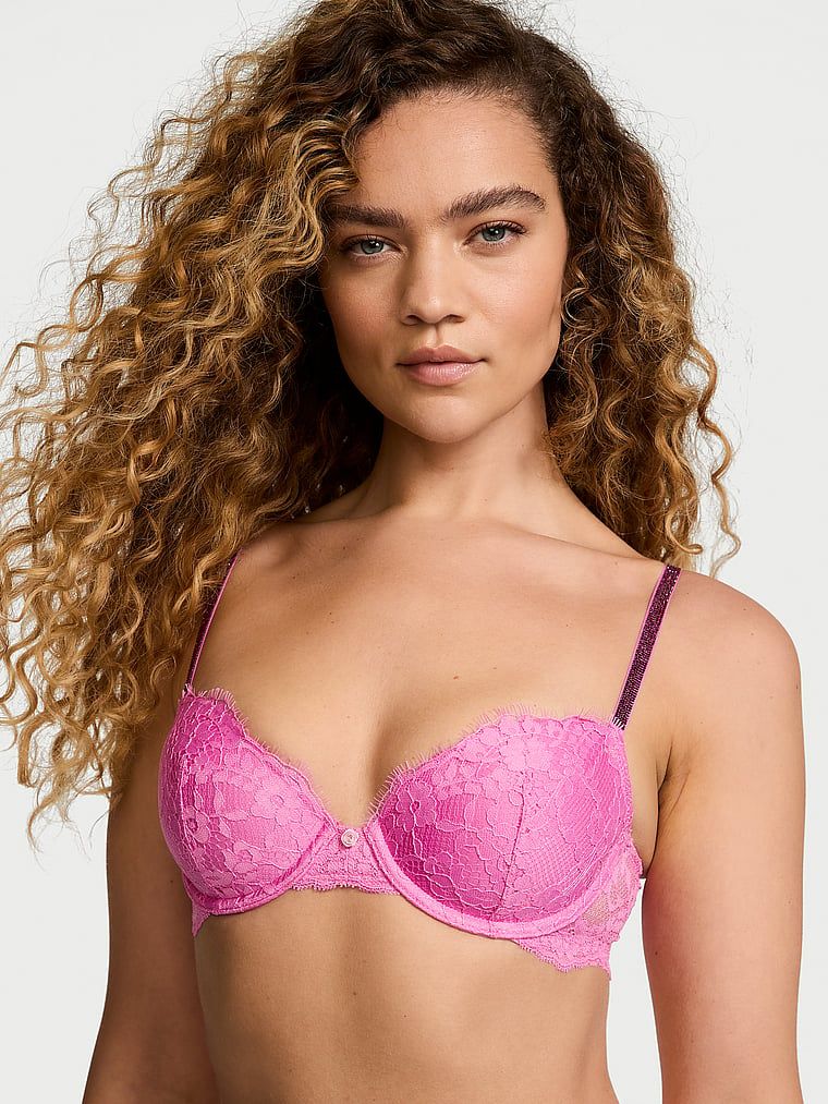 Modelka prezentuje biustonosz lekko usztywniany koronkowy z błyszczącymi ramiączkami Twinkle Strap Demi. Produkt ma kolor różowy i pochodzi z kolekcji Dream Angels.