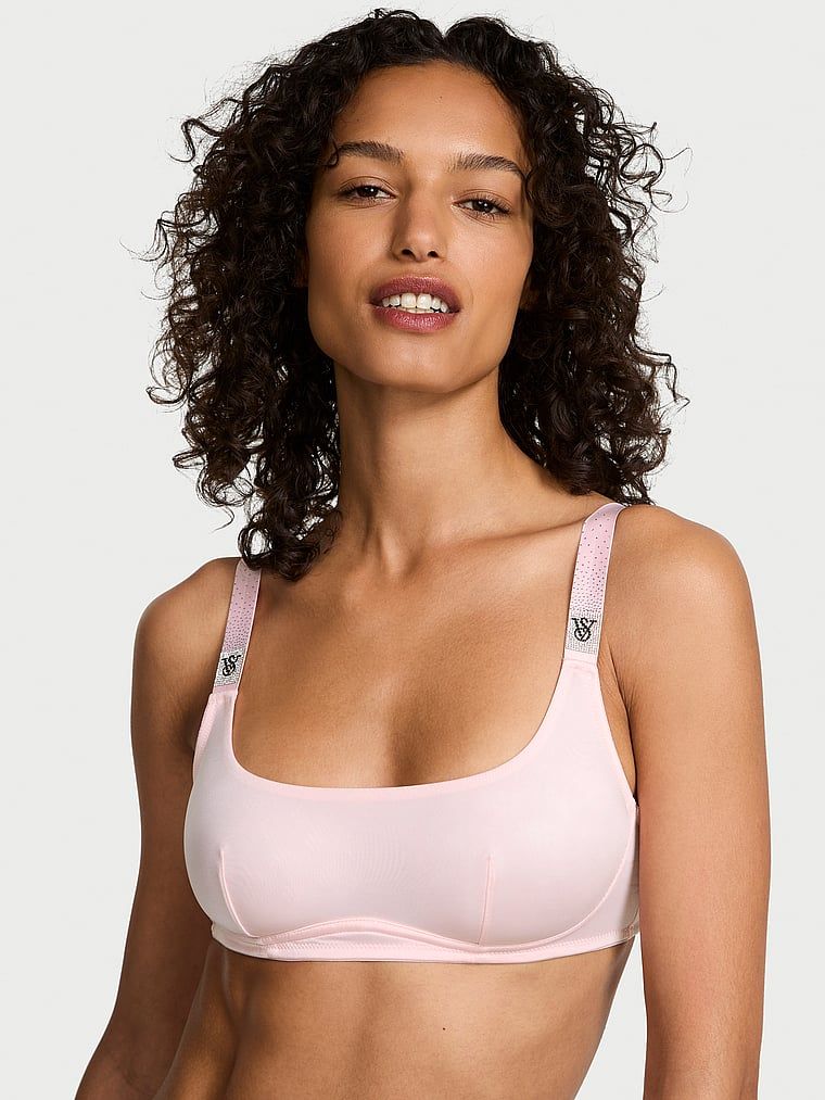 Modelka prezentuje biustonosz braletka bez fiszbin z błyszczącymi ramiączkami Shine Strap. Produkt ma kolor różowy i pochodzi z kolekcji Very Sexy.