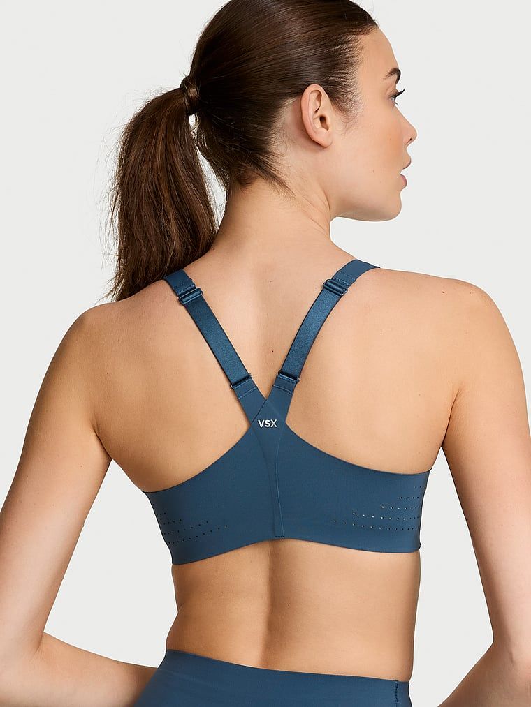 Modelka prezentuje biustonosz sportowy z maksymalnym podtrzymaniem z suwakiem Featherweight Max Front-Close. Produkt ma kolor niebieski i pochodzi z kolekcji VSX.