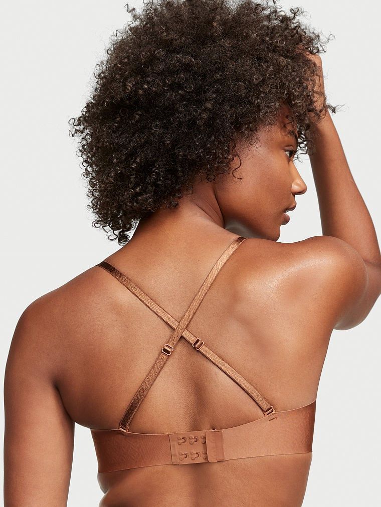 Modelka prezentuje biustonosz push-up bez ramiączek Sexy Illusions Uplift Strapless. Produkt ma kolor brązowy i pochodzi z kolekcji Victoria's Secret Bare.