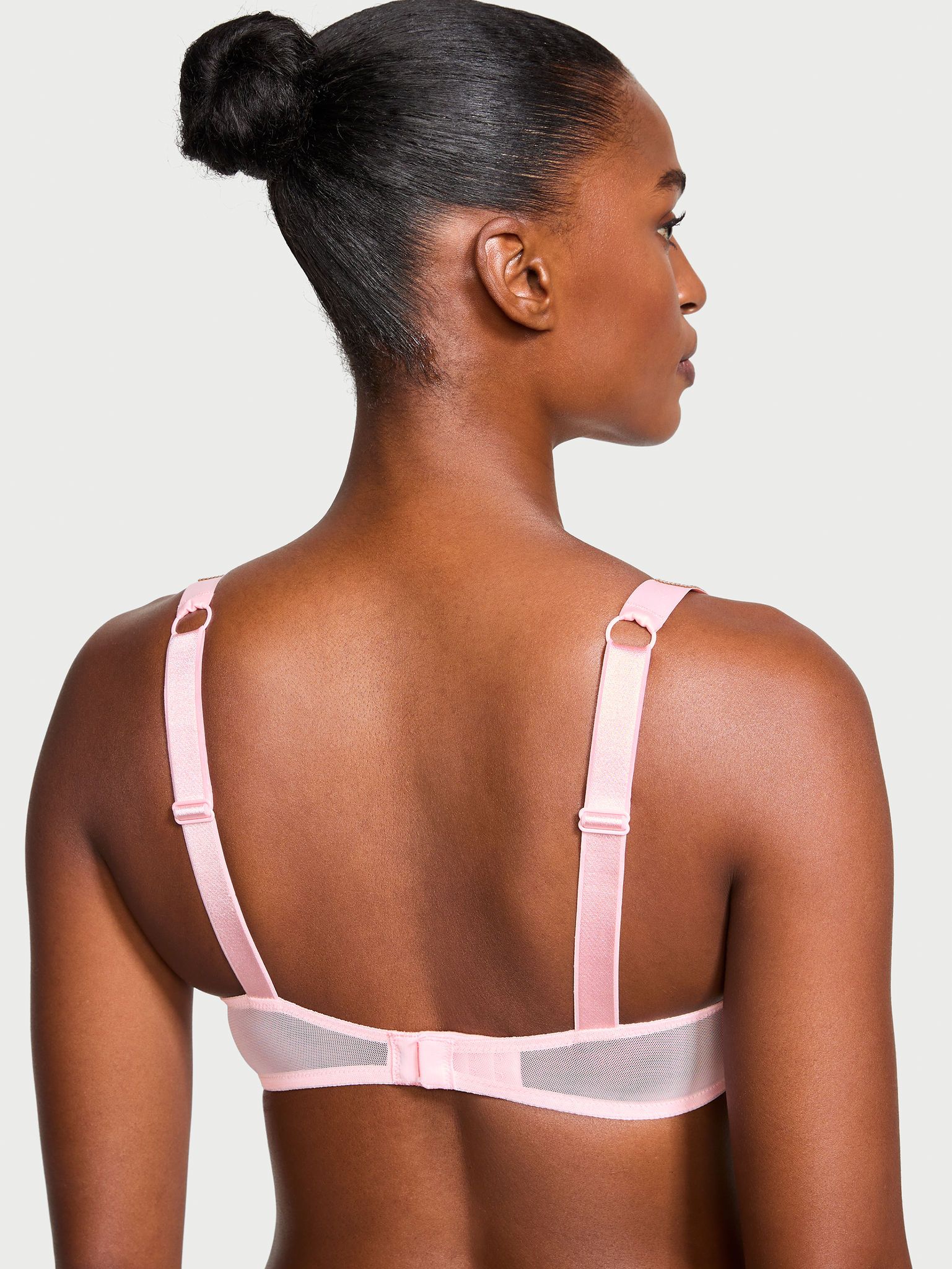 Modelka prezentuje biustonosz nieusztywniany koronkowy z błyszczącymi ramiączkami Shine Strap Demi. Produkt ma kolor różowy i pochodzi z kolekcji Very Sexy.