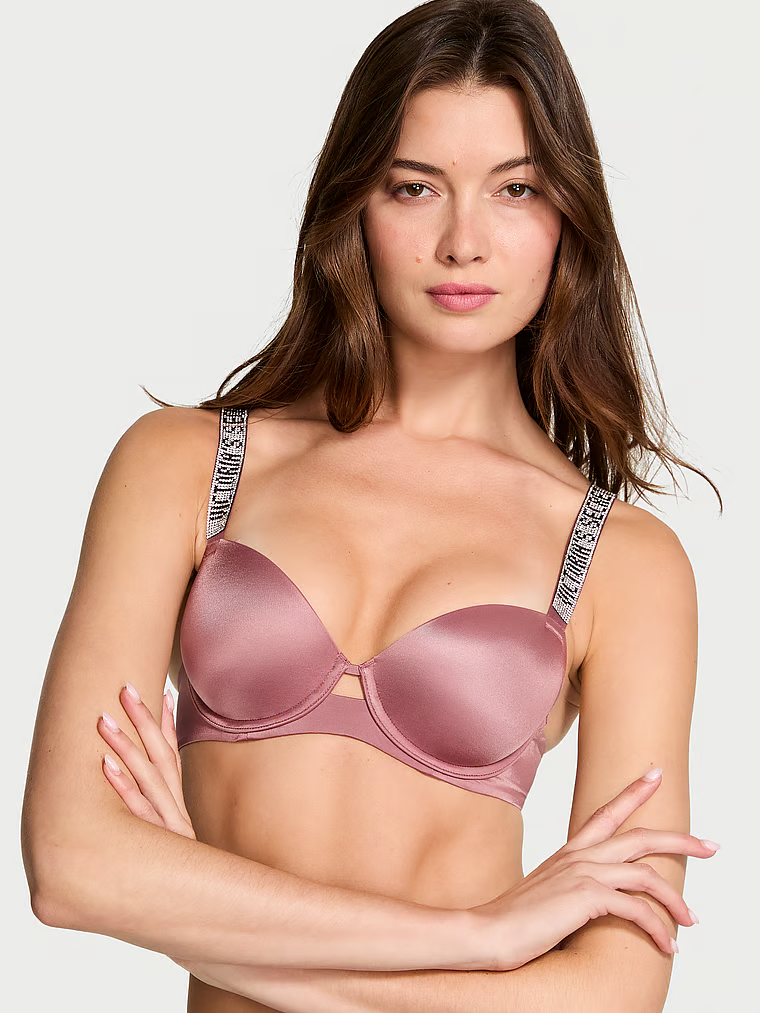 Modelka prezentuje biustonosz lekko usztywniany z błyszczącymi ramiączkami Shine Strap Demi. Produkt ma kolor różowy i pochodzi z kolekcji Very Sexy.