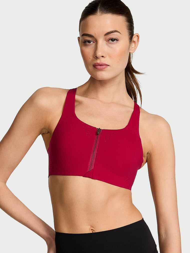 Modelka prezentuje biustonosz sportowy z maksymalnym podtrzymaniem z suwakiem Featherweight Max Front-Close. Produkt ma kolor czerwony i pochodzi z kolekcji VSX.